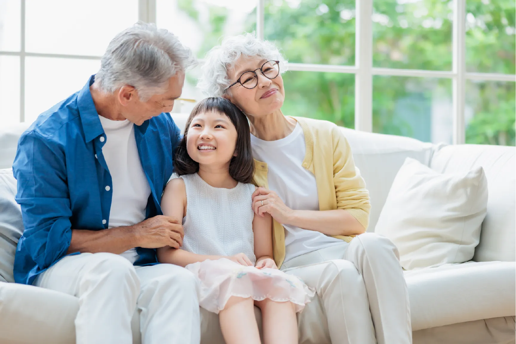 明るいリビングでくつろぐ三世代家族の様子