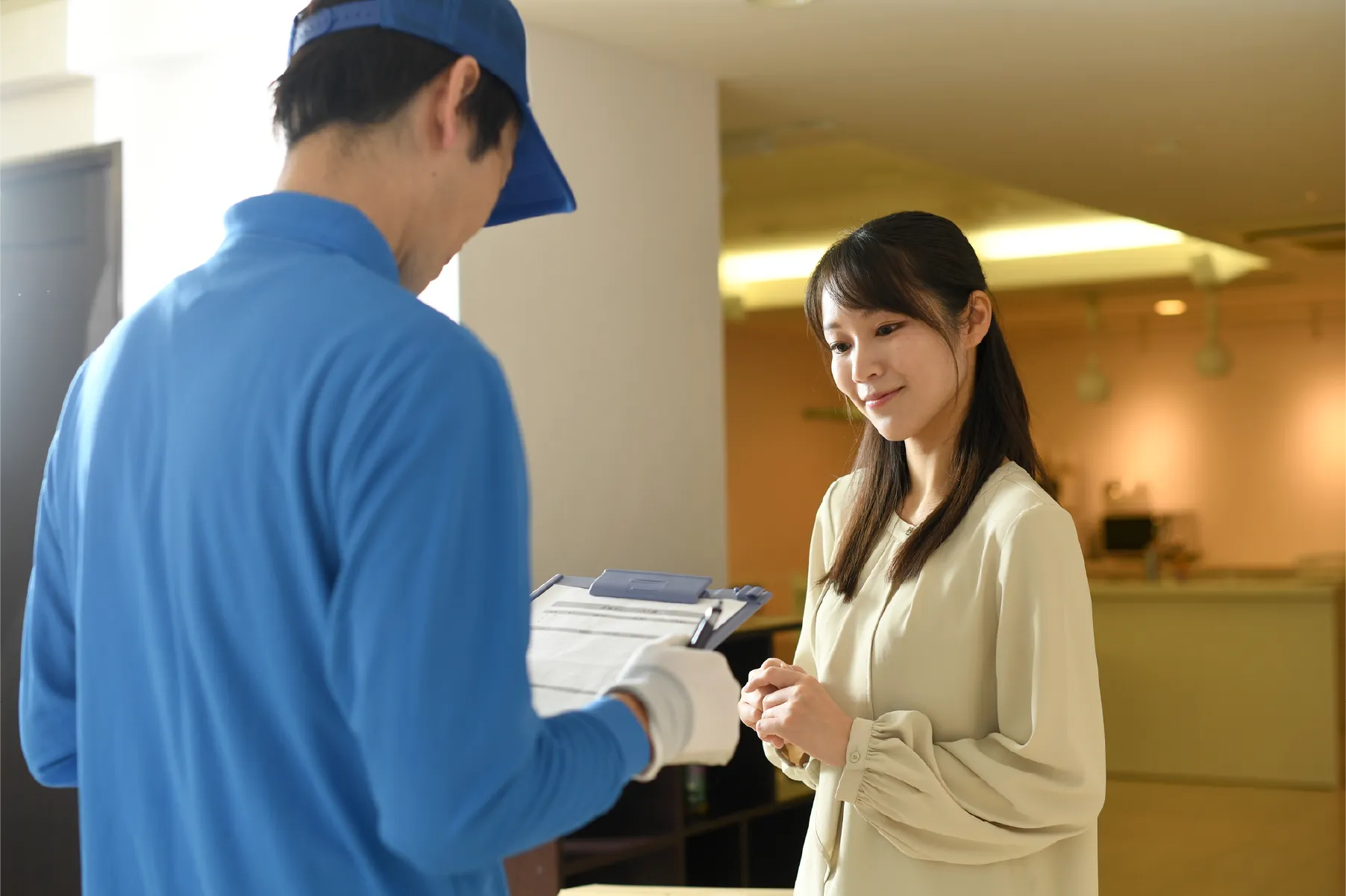 作業服のスタッフがお客様の玄関先で打ち合わせをしている様子