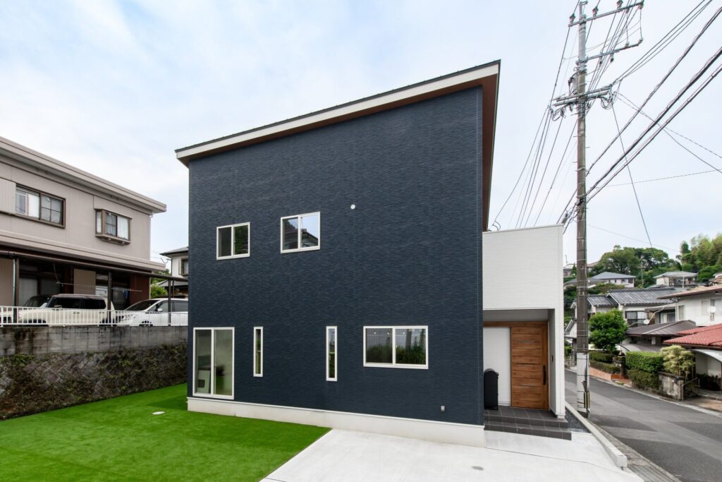 ネイビーの外壁と片流れ屋根が印象的な、都会的で洗練された二階建ての住まい